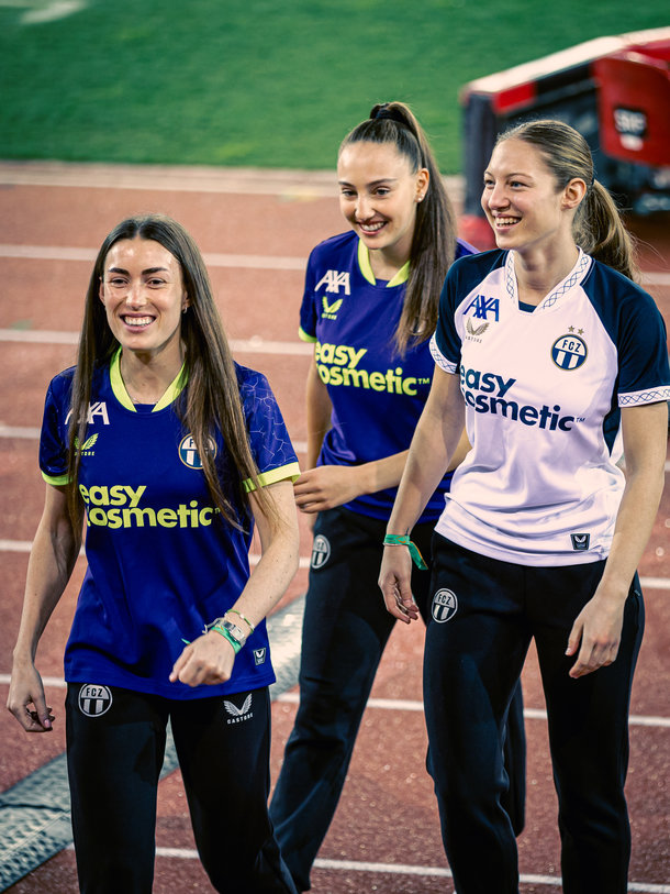 Drei Spielerinnen der FC Zürich Frauen laufen gemeinsam in Trikots mit easycosmetic Logo am Spielfeldrand.